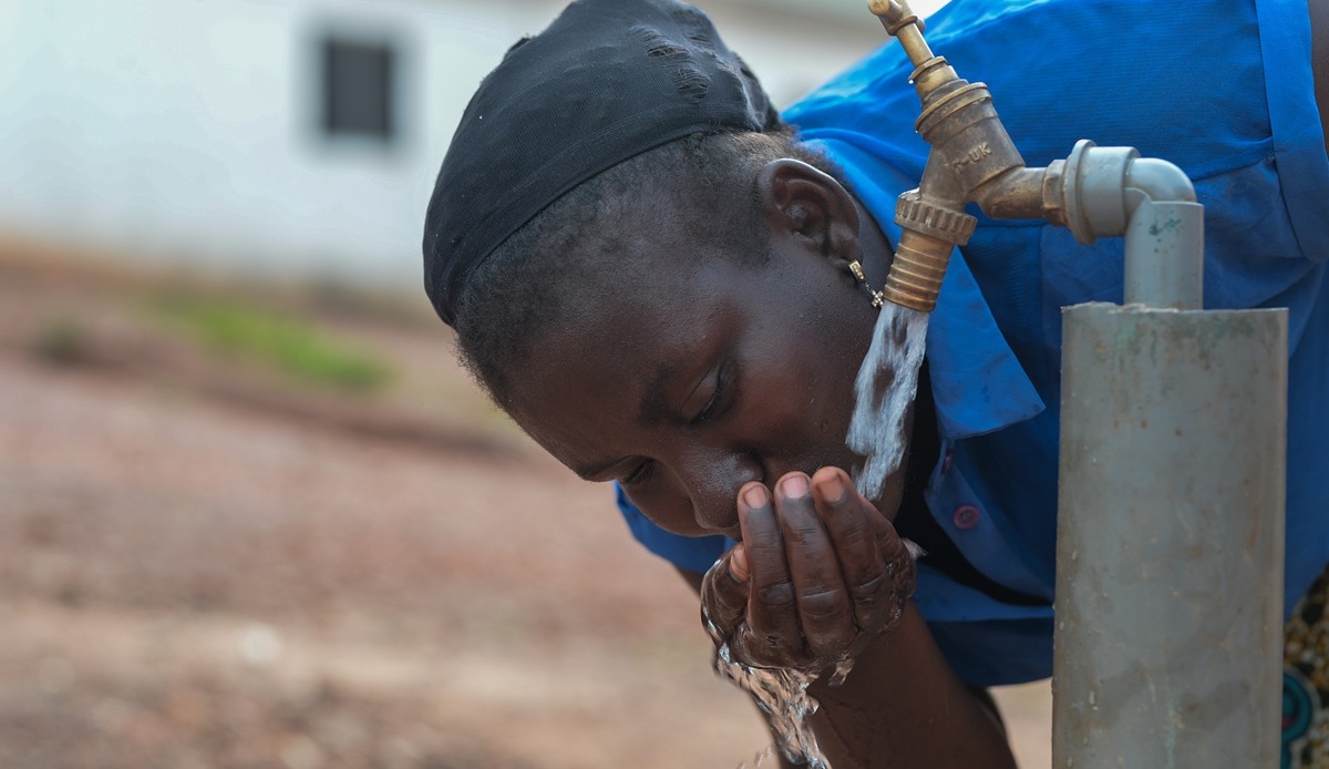 Girl in blue dress drinking water from tap Girl in blue dress drinking water from tap