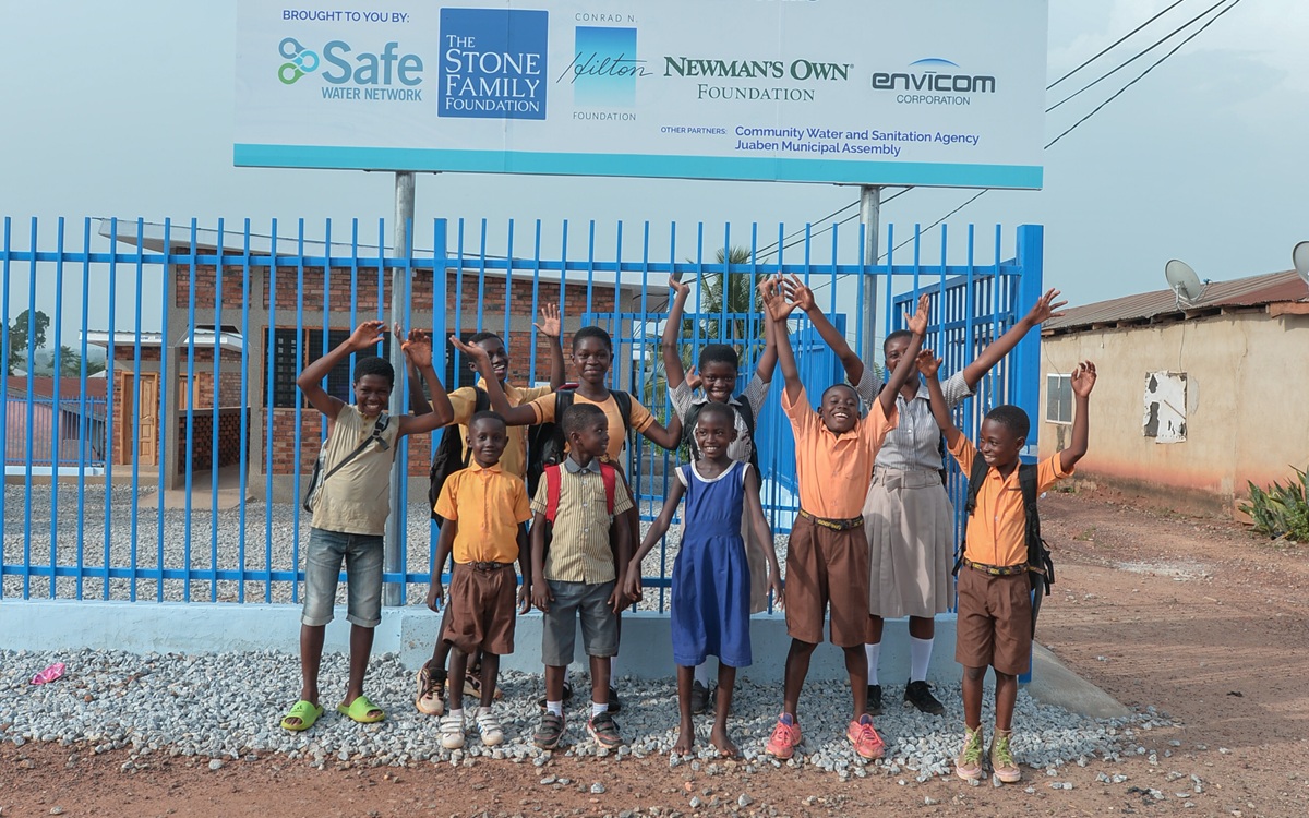 Kids with arms in the air in front of HOME poster Kids with arms in the air in front of HOME poster